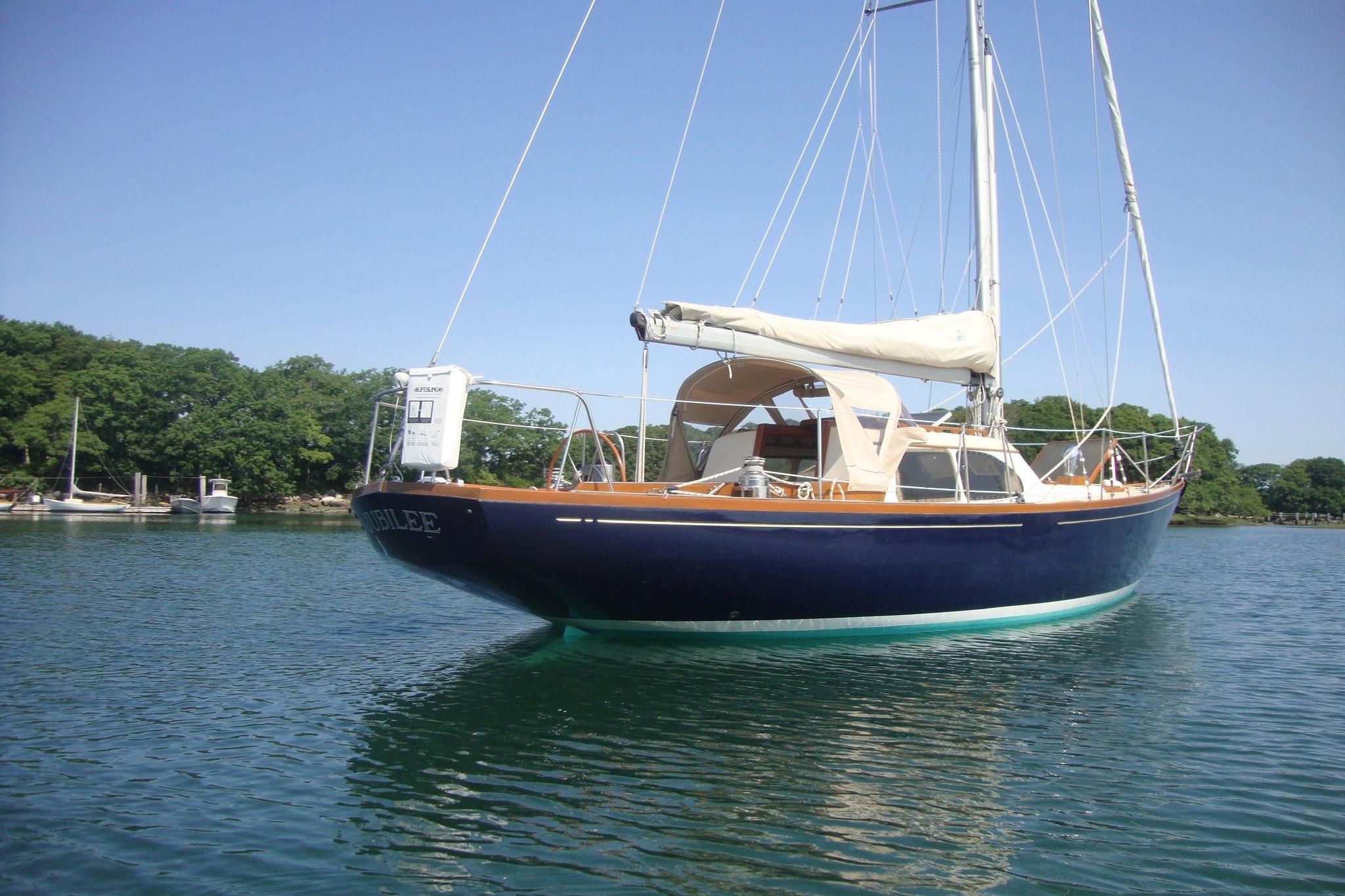 1967 Columbia Constellation sailboat on calm water, surrounded by lush greenery.