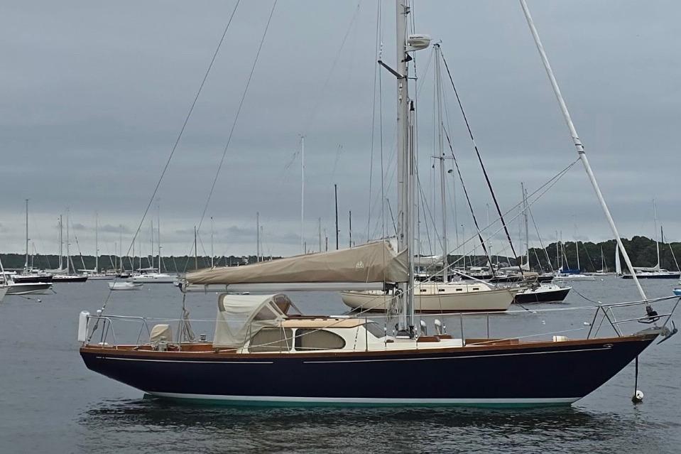 1967 Columbia Constellation sailboat anchored in a marina with overcast skies.