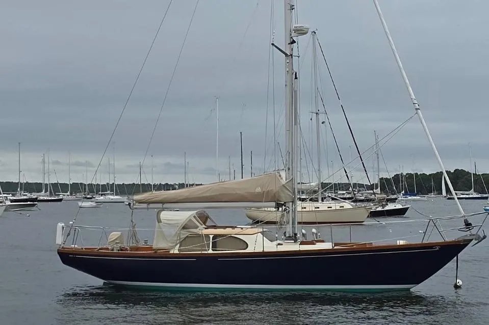 1967 Columbia Constellation sailboat anchored in a marina with overcast skies.