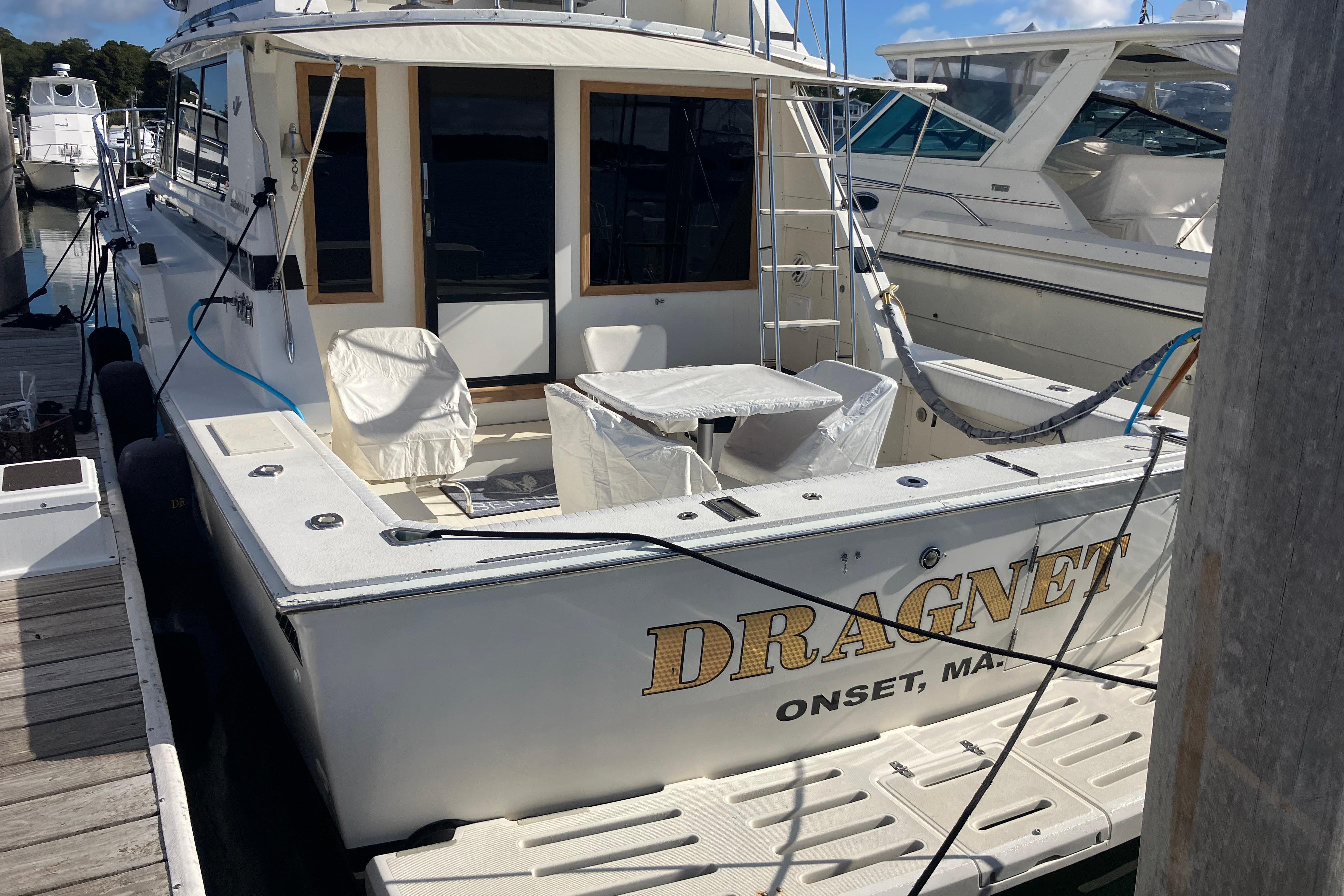 1987 Bertram 42 Convertible boat named Dragnet docked at marina.