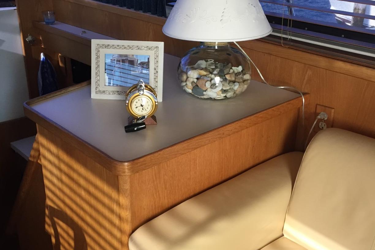 Interior of 1987 Bertram 42 Convertible with lamp, clock, and framed photo on table.