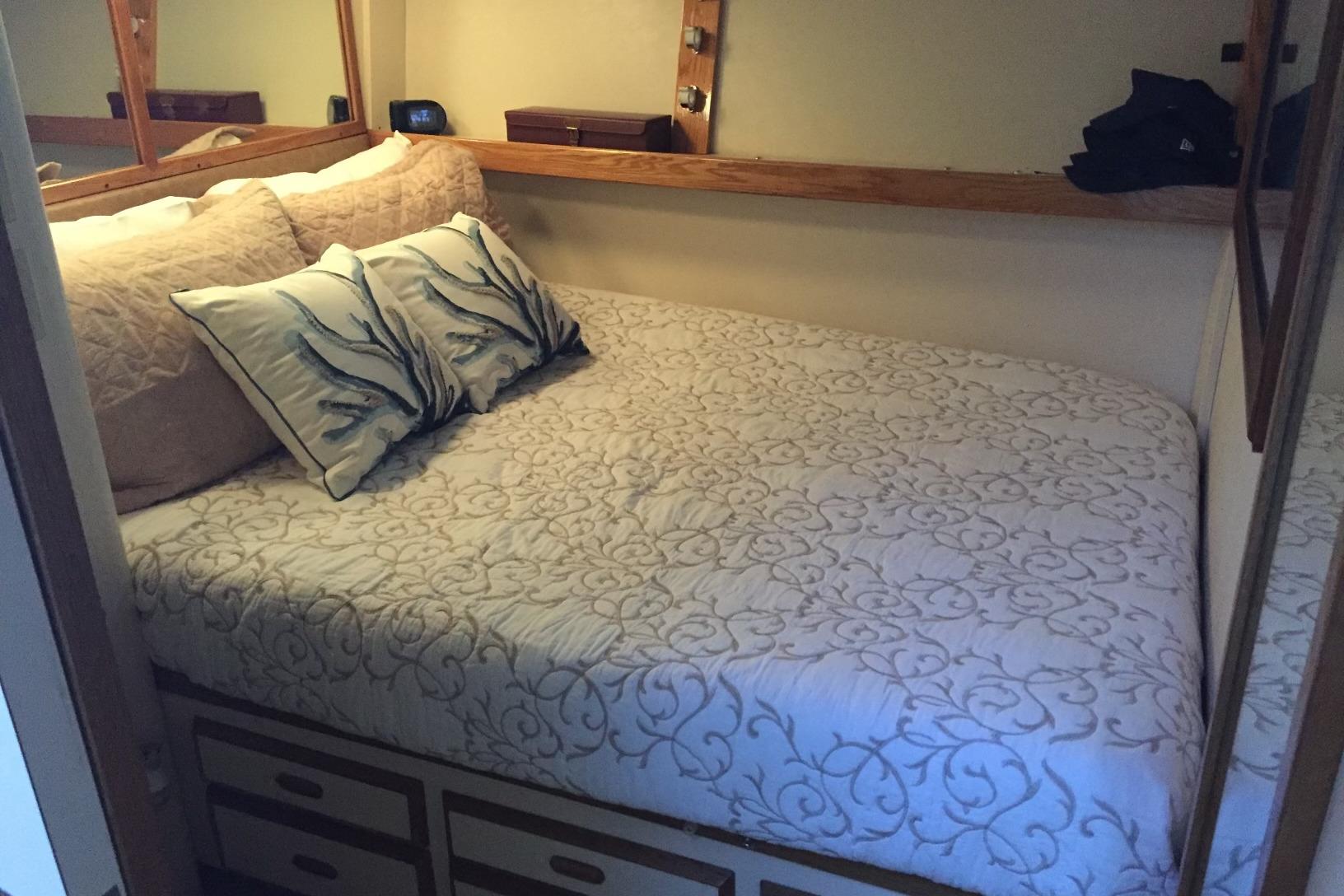 Cozy bedroom in 1987 Bertram 42 Convertible yacht with elegant bedding and pillows.