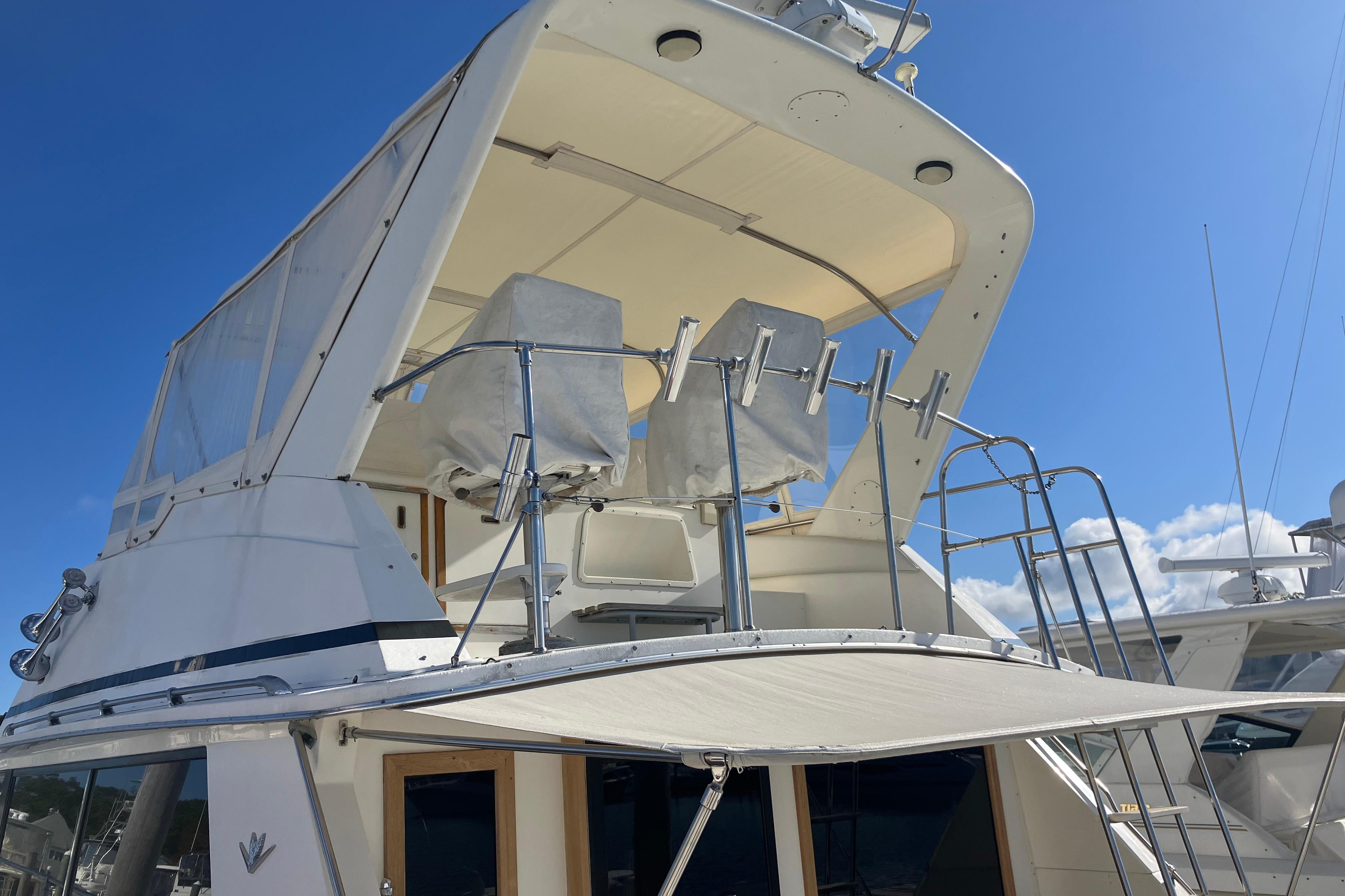 1987 Bertram 42 Convertible yacht with covered flybridge under clear blue sky.