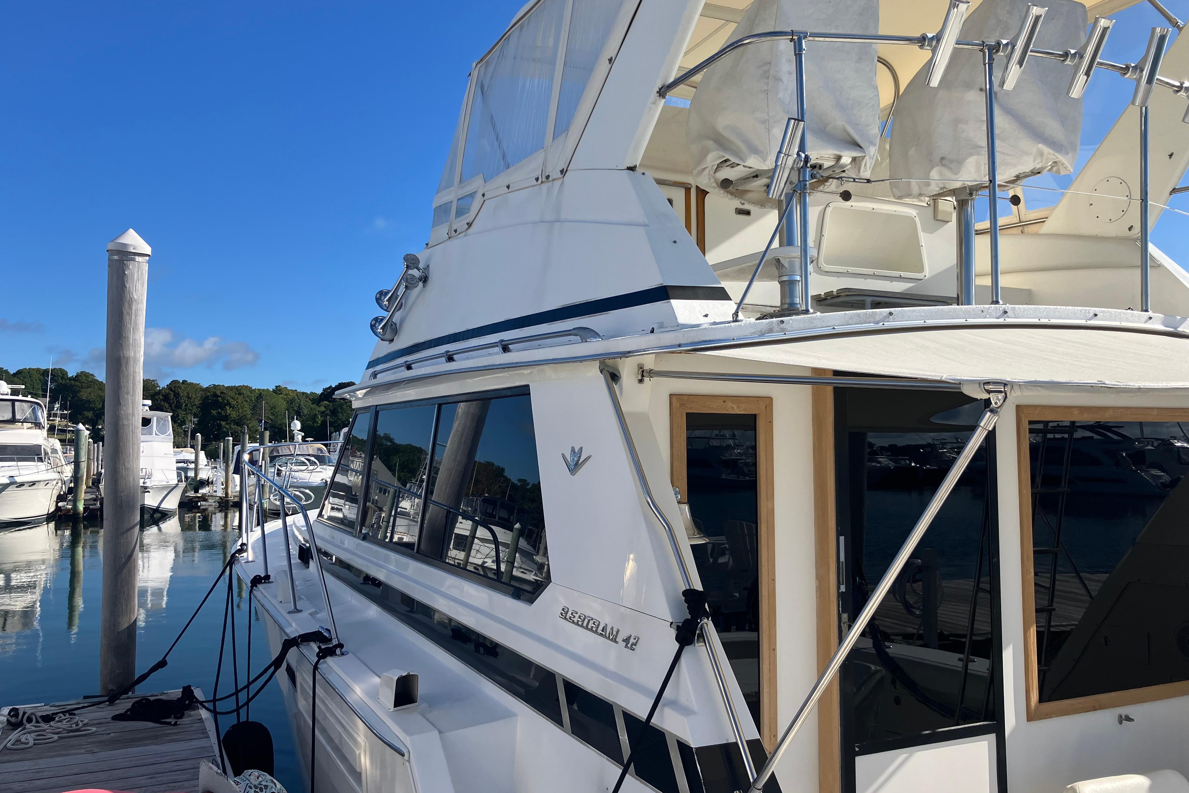 1987 Bertram 42 Convertible yacht docked at marina under clear blue sky.