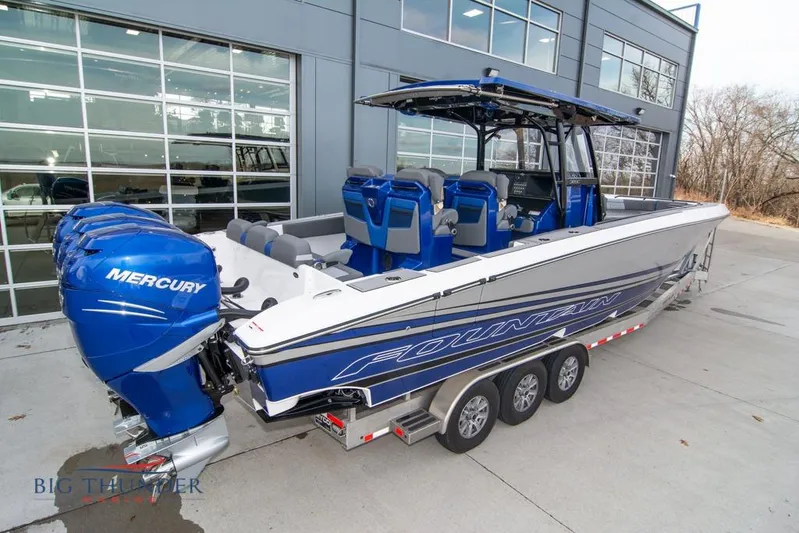  Yacht Photos Pics 2022 Fountain 38 SC boat with triple Mercury engines, parked outside a modern building.