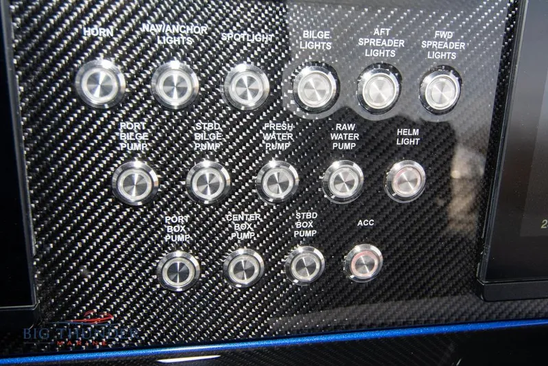  Yacht Photos Pics Control panel of 2022 Fountain 38 SC boat with various switches and carbon fiber finish.
