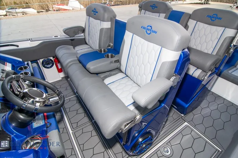  Yacht Photos Pics 2022 Fountain 38 SC boat interior with gray and blue seating, steering wheel, and cup holders.