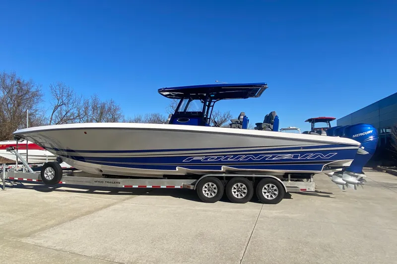  Yacht Photos Pics 2022 Fountain 38 SC boat on trailer, blue and white design, clear sky background.