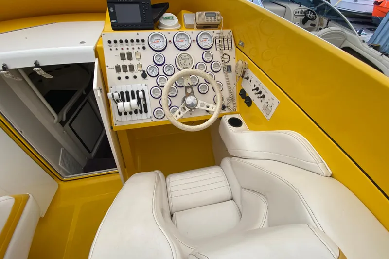  Yacht Photos Pics Cockpit of a 1999 Fountain 47 Lightning boat with yellow dashboard and white seating.