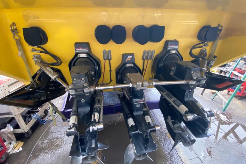  Yacht Photos Pics 1999 Fountain 47 Lightning boat with triple MerCruiser outdrives in a workshop setting.