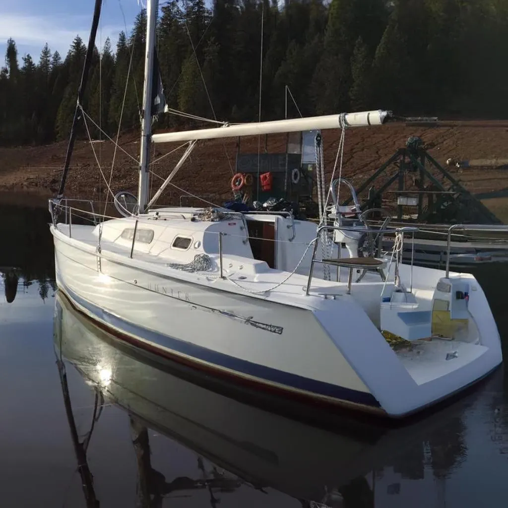 2008 Hunter 27 sailboat on calm water, surrounded by trees.