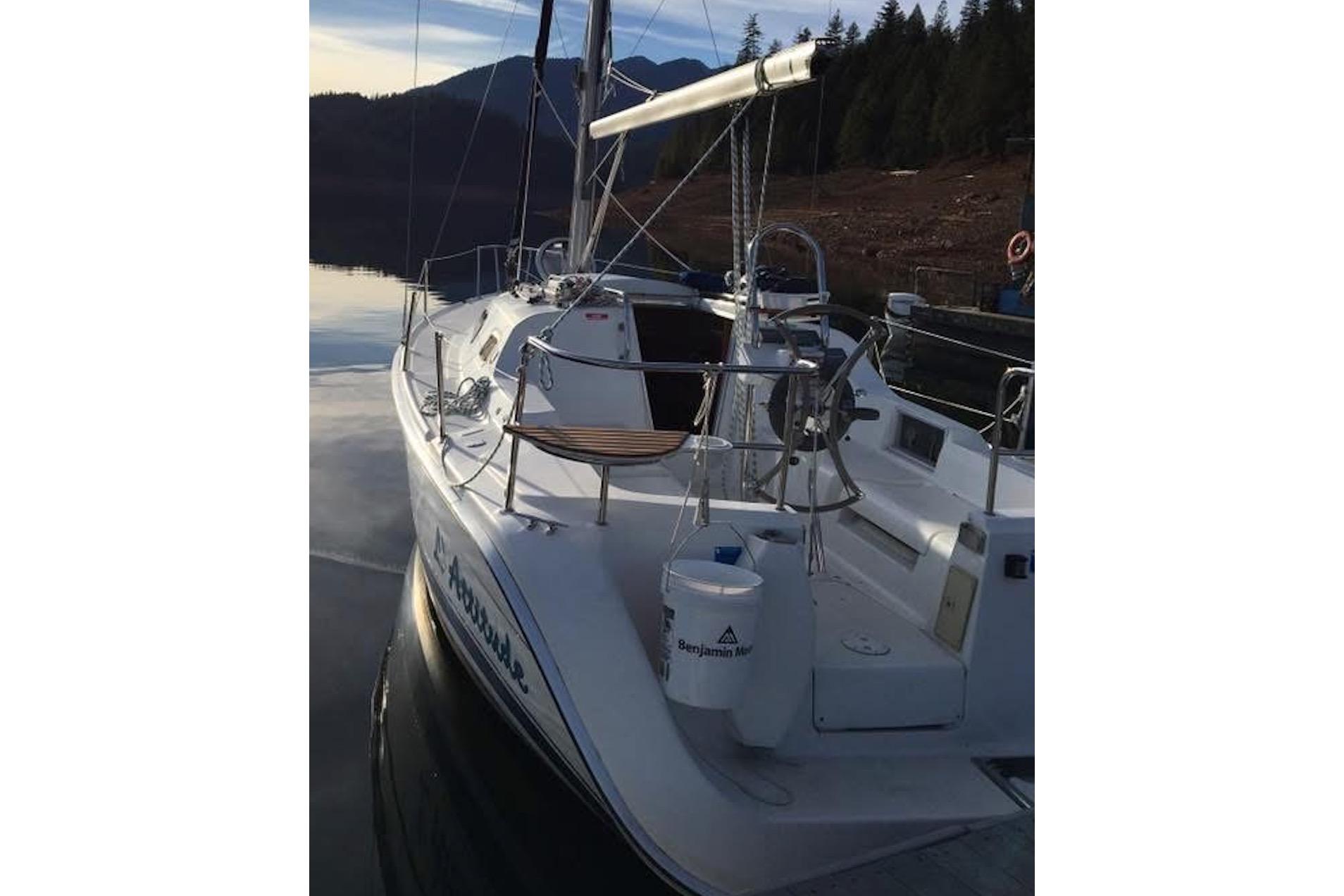 2008 Hunter 27 sailboat docked on a serene lake with forested hills.