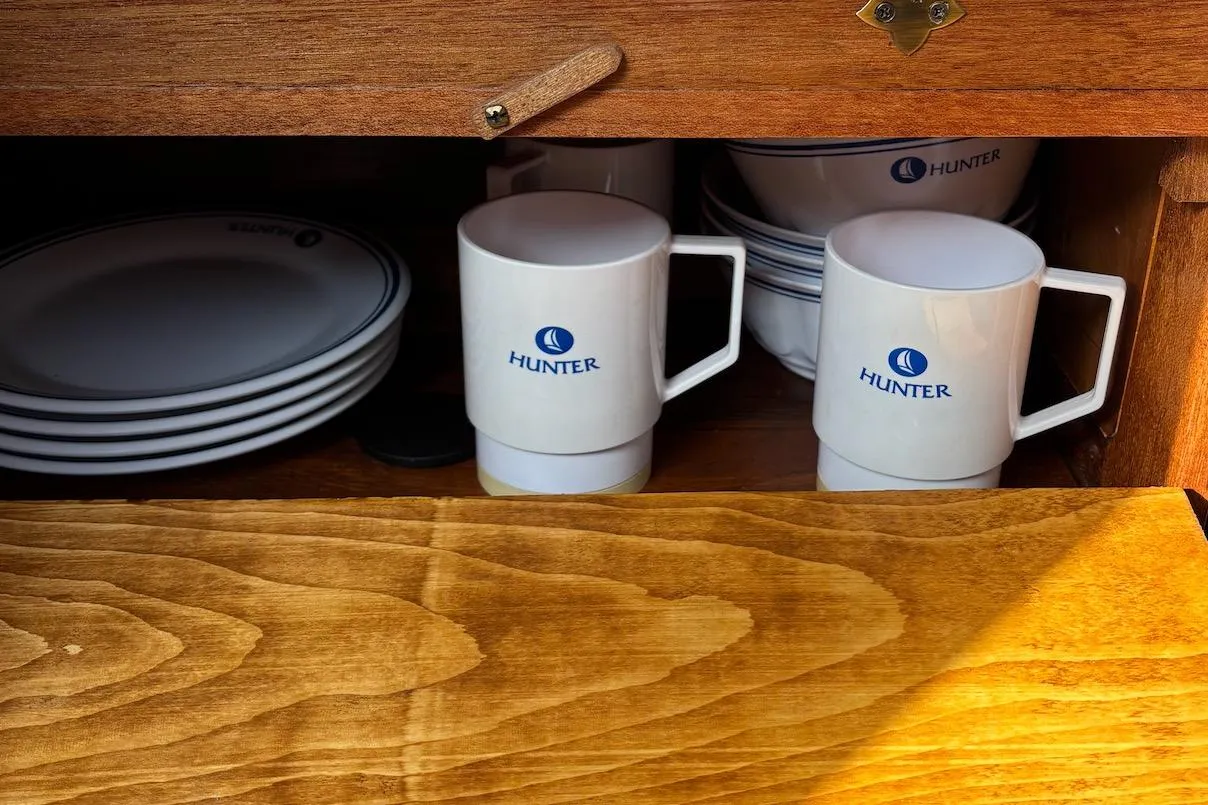 Wooden cabinet with Hunter-branded mugs and plates, model 27, year 2008.