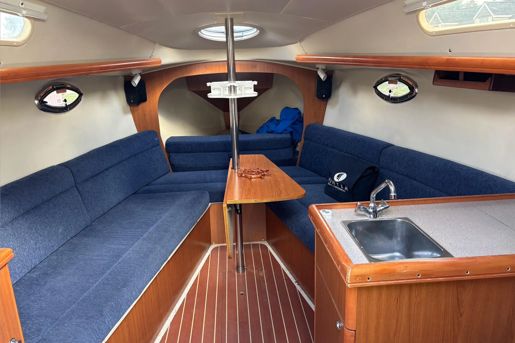 Interior of a 2008 Hunter 27 sailboat with blue seating and wooden finishes.