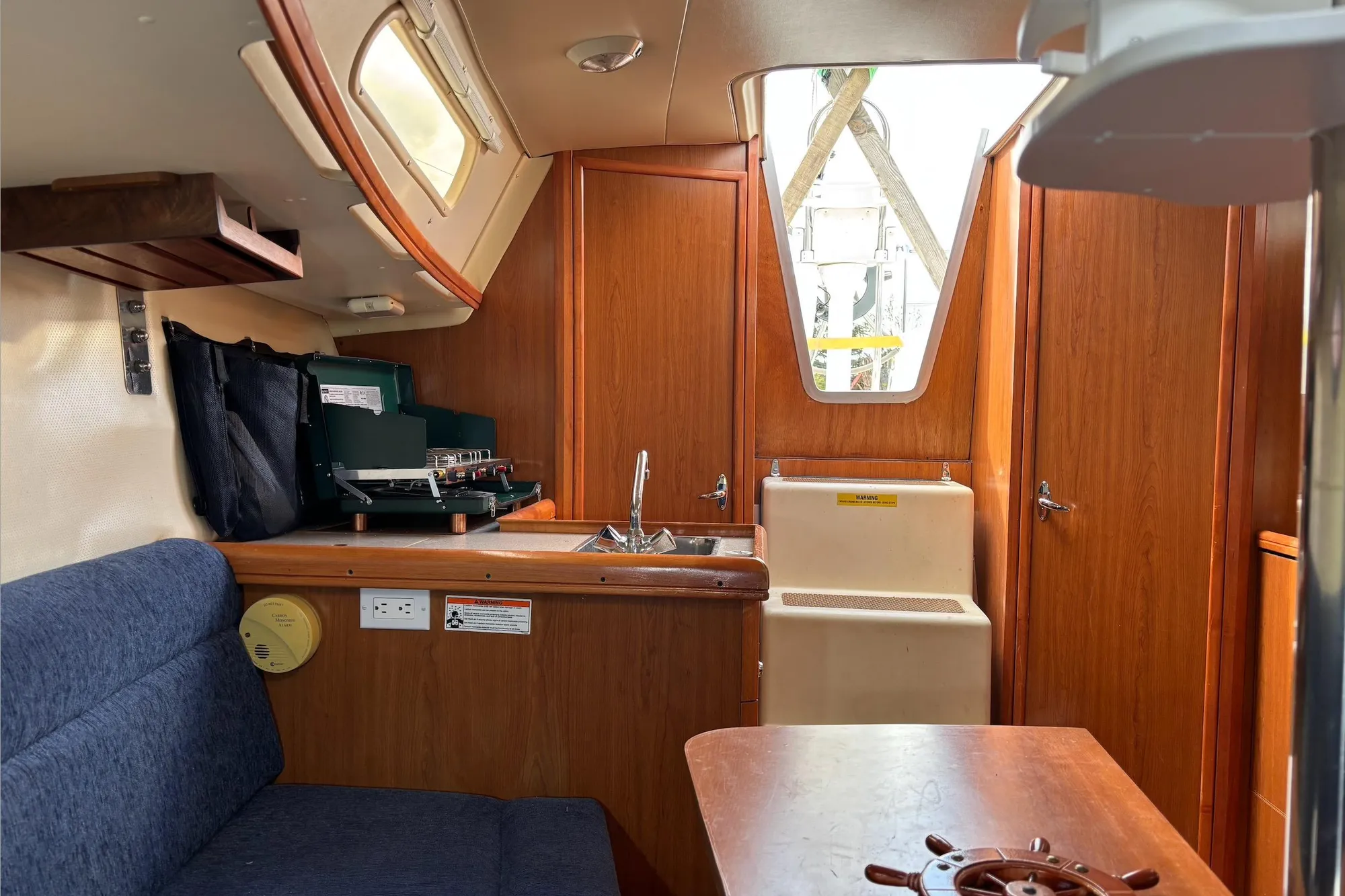 Interior of 2008 Hunter 27 sailboat with wooden cabinetry and compact kitchen area.