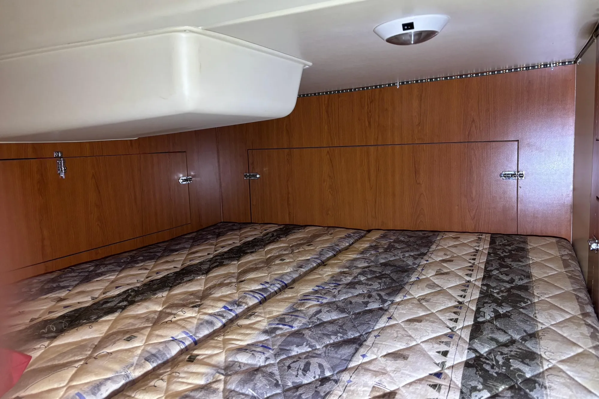 Interior cabin of a 2008 Hunter 27 sailboat with wood paneling and a patterned bedspread.