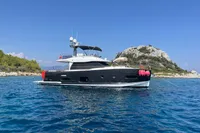 Azimut Magellano 53 yacht, 2017 model, anchored in clear blue waters near a rocky island.