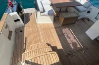 2017 Azimut Magellano 53 yacht deck with seating and table, near rocky shoreline.