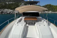 Azimut Magellano 53 yacht, 2017 model, anchored near rocky coastline under clear blue sky.