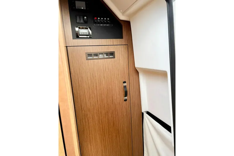  Yacht Photos Pics Interior view of 2021 Jeanneau NC 37 yacht with wooden cabinetry and control panel.