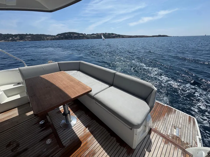  Yacht Photos Pics Luxurious 2023 Prestige 460 yacht deck with seating, table, and ocean view.