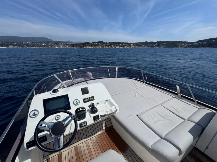  Yacht Photos Pics Prestige 460 yacht helm and sunbed, 2023 model, cruising on open sea with scenic coastline.