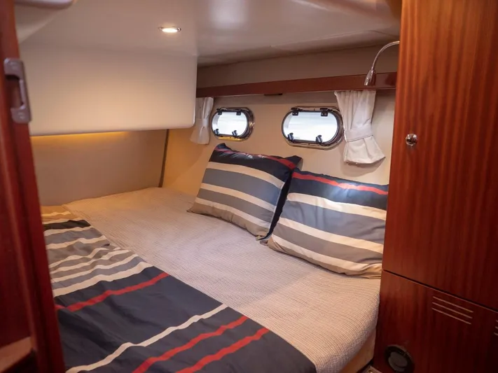 Seahawk Yacht Photos Pics Cozy cabin interior of 2017 Nimbus 405 Flybridge with striped bedding and porthole windows.