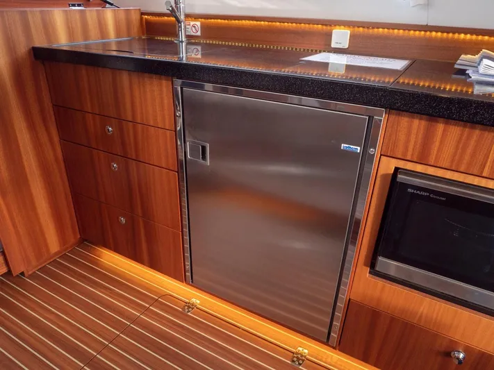 Seahawk Yacht Photos Pics Luxurious kitchen area in 2017 Nimbus 405 Flybridge yacht with wood cabinetry and stainless steel appliances.