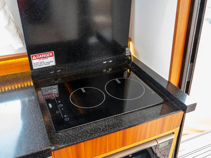 Seahawk Yacht Photos Pics Modern kitchen stove on 2017 Nimbus 405 Flybridge yacht, featuring sleek black countertop.