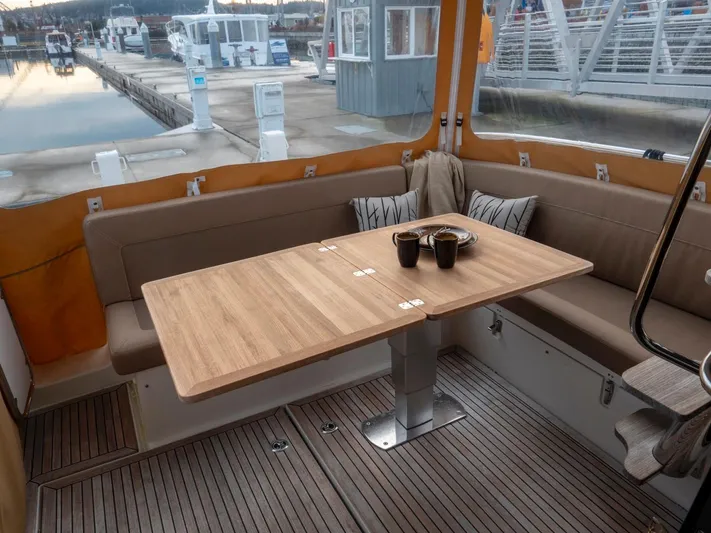 Seahawk Yacht Photos Pics Cozy seating area on 2017 Nimbus 405 Flybridge yacht with wooden table and cushions.