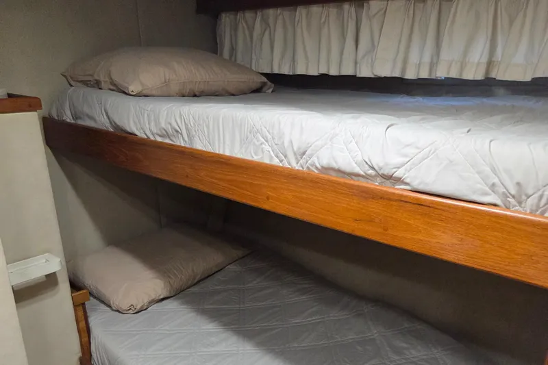 Pazzaz Yacht Photos Pics Bunk beds in 1985 Chris-Craft 500 Constellation Motor Yacht cabin, featuring wooden frames and white bedding.