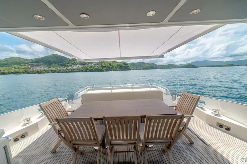 Carpe Diem Yacht Photos Pics Luxury Azimut 77S yacht deck with dining area, overlooking serene ocean and lush green hills.