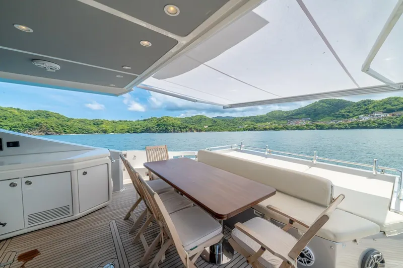 Carpe Diem Yacht Photos Pics Luxurious 2017 Azimut 77S yacht deck with dining area, overlooking serene waters and lush green hills.