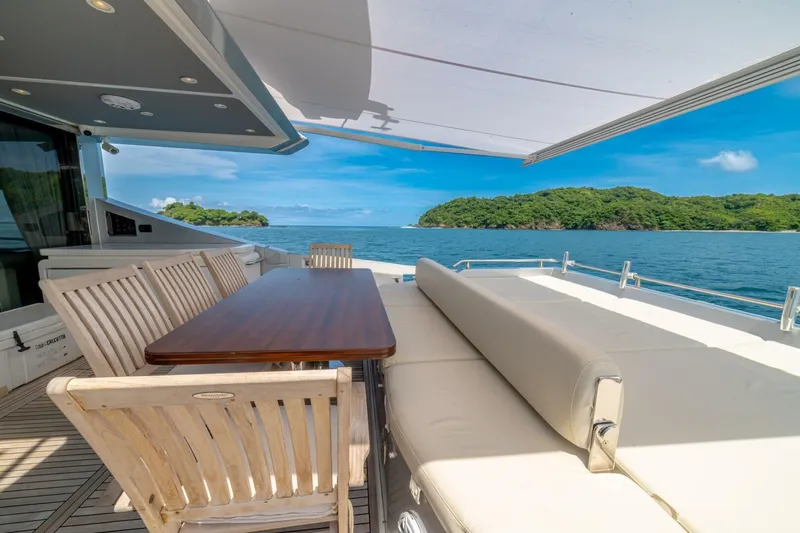 Carpe Diem Yacht Photos Pics Luxurious 2017 Azimut 77S yacht deck with dining area, overlooking serene ocean and lush island.