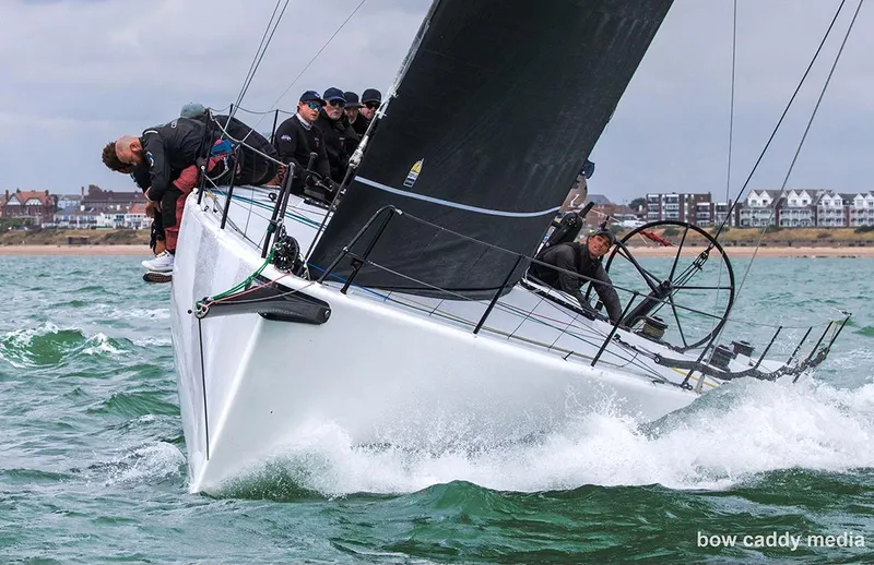 Zen - Formerly Synergy, Sorcha Yacht Photos Pics Sailing crew on Botin TP 52 yacht navigating choppy waters near coastal town.