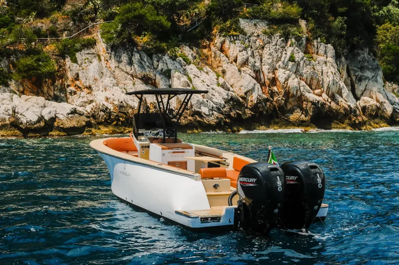  Yacht Photos Pics 2025 Lilybaeum Levanzo 25 Lounge Deck boat on clear water near rocky shoreline.