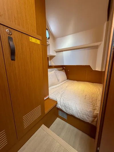 Demo Yacht Photos Pics Cozy cabin interior of 2025 Beneteau Swift Trawler 48 with wooden finishes and comfortable bedding.