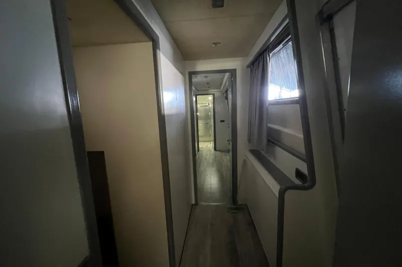M/y Q Yacht Photos Pics Dimly lit hallway inside a 2001 Falcon 106 yacht, featuring wooden flooring and side window.