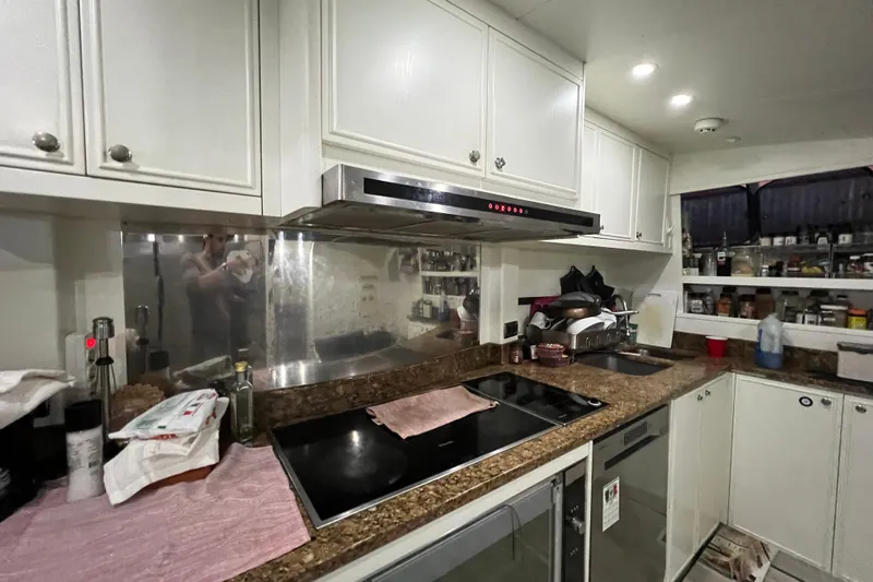 M/y Q Yacht Photos Pics Modern kitchen with white cabinets, stainless steel appliances, and granite countertops in a Falcon 106 yacht.
