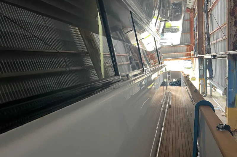 M/y Q Yacht Photos Pics Side view of a 2001 Falcon 106 yacht in a shipyard, showcasing sleek design and wooden deck.