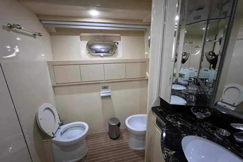 M/y Q Yacht Photos Pics Luxurious yacht bathroom with dual toilets, marble countertop, and porthole window in Falcon 106, 2001.
