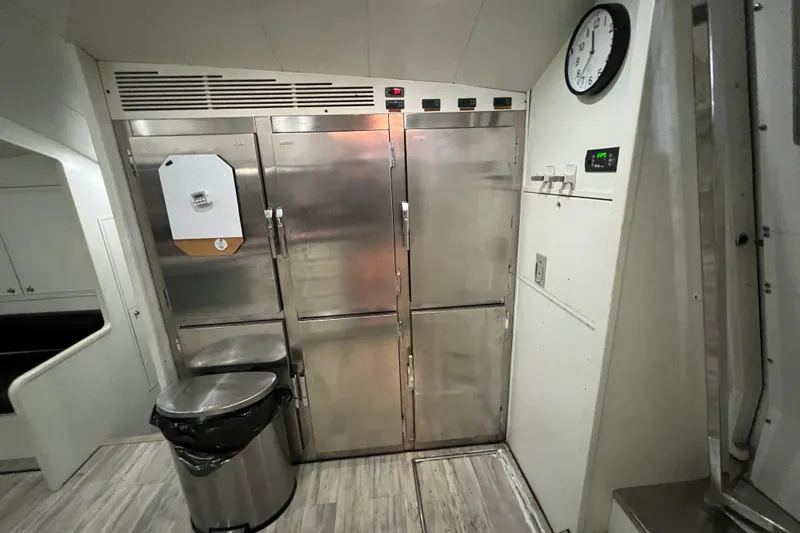 M/y Q Yacht Photos Pics Galley kitchen with stainless steel appliances, clock, and trash can in a Falcon 106 yacht.