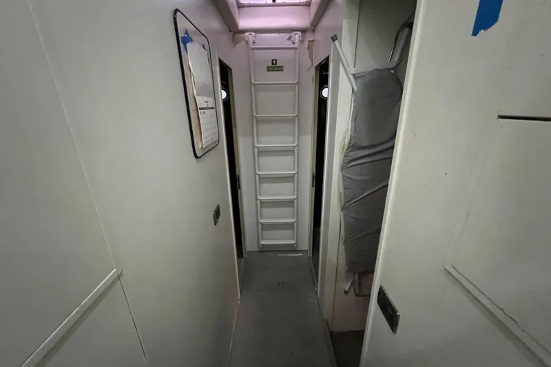 M/y Q Yacht Photos Pics Narrow corridor inside a 2001 Falcon 106 yacht, featuring a ladder and storage area.