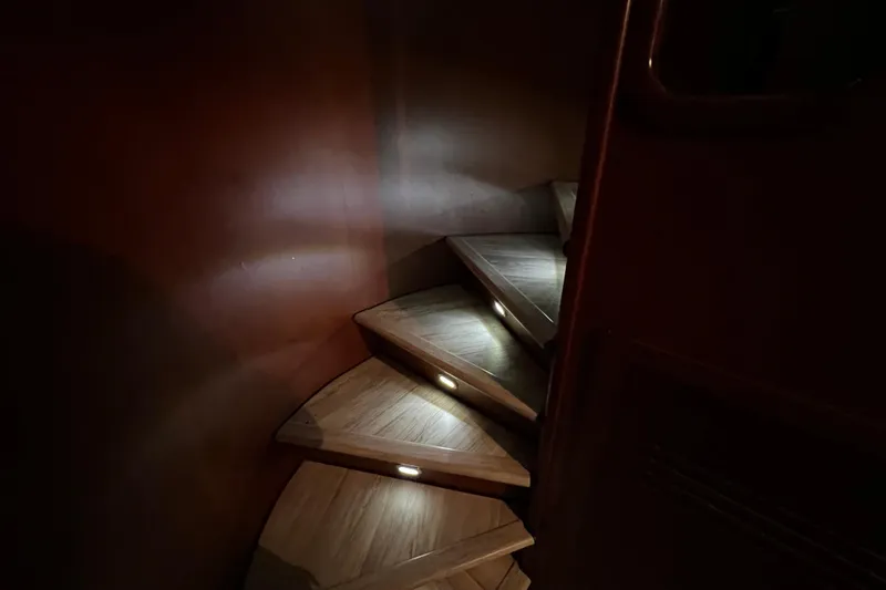M/y Q Yacht Photos Pics Dimly lit wooden spiral staircase on Falcon 106 yacht, 2001 model.