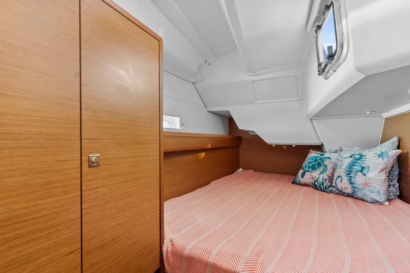 Deep Blue Yacht Photos Pics Cozy cabin interior of 2020 Jeanneau Sun Odyssey 389 with wooden finish and patterned bedding.