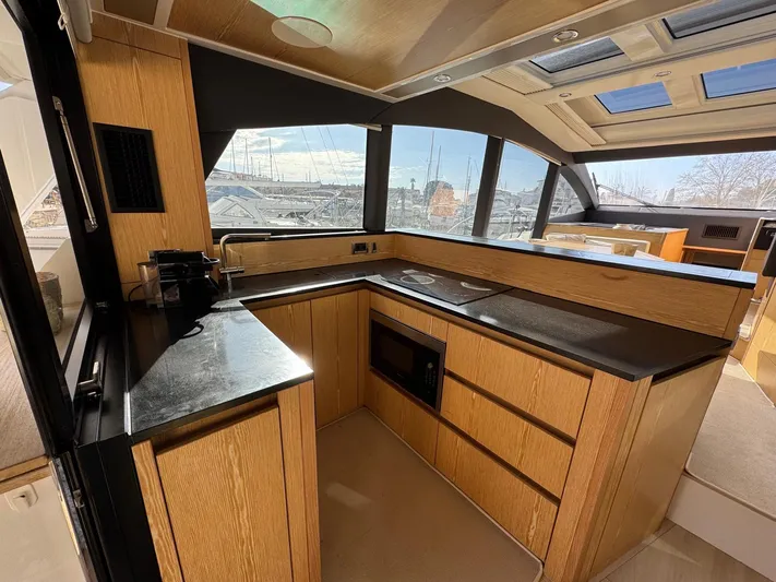 Sealine C530 Yacht Photos Pics Luxurious kitchen interior of 2017 Sealine C530 yacht with modern wood cabinetry and large windows.