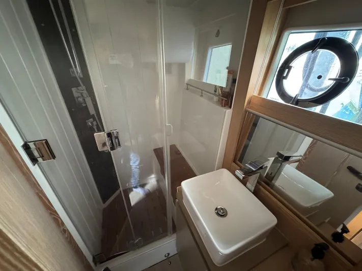 Sealine C530 Yacht Photos Pics 2017 Sealine C530 yacht bathroom with shower, sink, mirror, and porthole window.