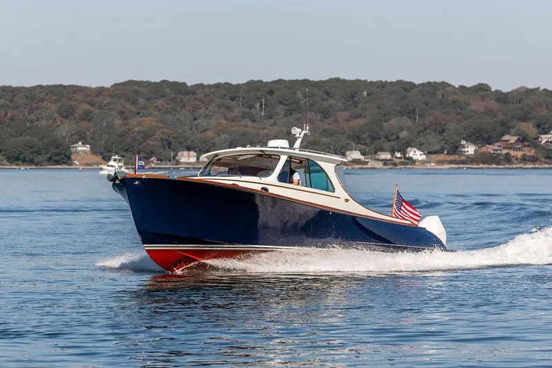 Carol I Yacht Photos Pics 2024 Hinckley 35 boat cruising on a calm lake with scenic shoreline background.