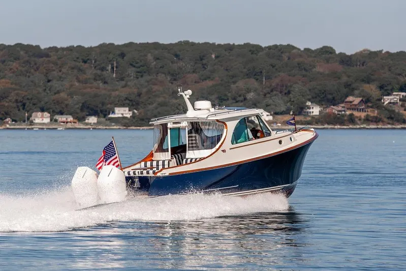 Carol I Yacht Photos Pics 2024 Hinckley 35 boat cruising on a calm lake with scenic forest backdrop.
