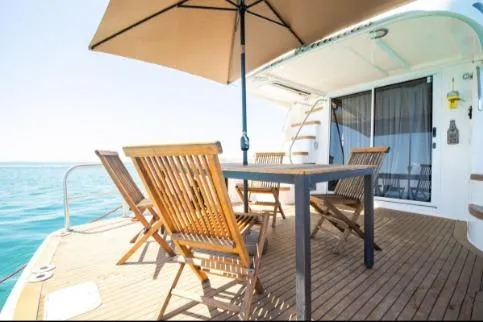 Salty Pause Yacht Photos Pics 2005 Sea Ray 420 Sedan Bridge yacht deck with wooden chairs and table under umbrella.